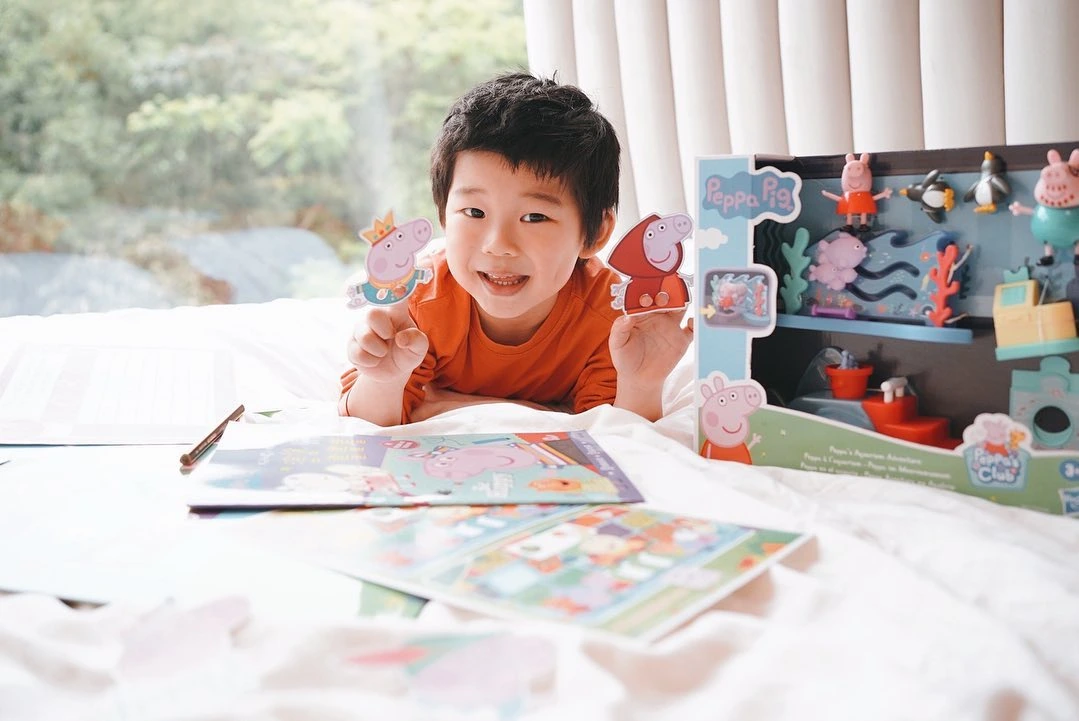 A child with Peppa Pig books and character activities from Stay Home with Peppa